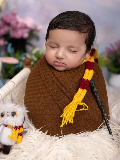 Our little wizard is dreaming of Hogwarts. This close-up shows the details of our Harry Potter theme, from the knitted scarf to the tiny wand, perfect for fans of the series.