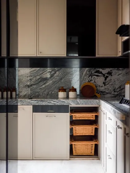 The kitchen is separated from the living area by a grey-tinted glass partition, creating a sense of privacy while maintaining a visual connection.