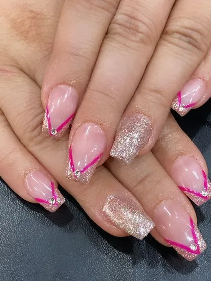 A modern take on a French manicure with a sheer base, pink V-tips, and a sparkling glitter accent nail.