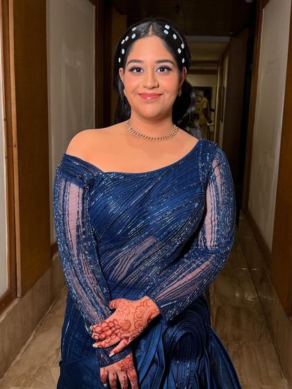 A lovely portrait of the client, showcasing her complete party-ready look. The makeup is balanced, with the bold eye making a statement against her elegant blue dress.