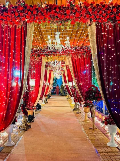A classic and opulent entrance passage created with rich red and gold drapes. The path is lit by chandeliers and fairy lights, giving guests a royal welcome as they enter the celebration.