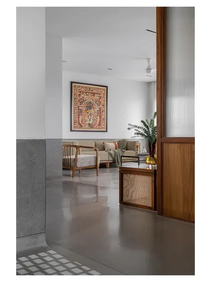A glimpse into a living area from the corridor, where traditional Indian art and rattan-accented furniture create a culturally rich and contemporary space.