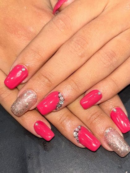 A vibrant pink set with gold glitter accent nails and rhinestone detailing, perfect for a party.