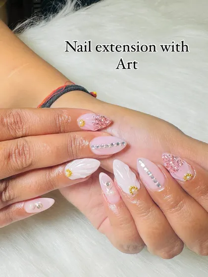 A closer look at these detailed nail extensions. You can see the combination of pink glitter, silver stone lines, and white textured art.