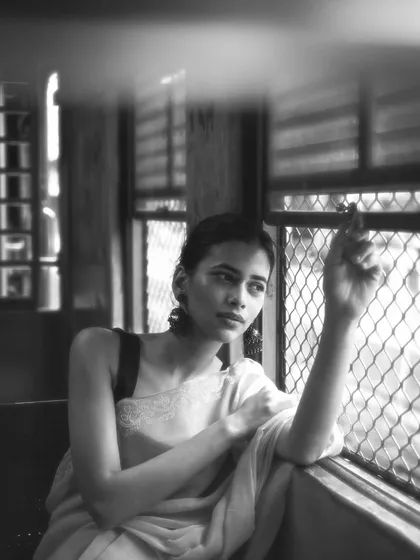 The textures of the old train window and the soft light create a timeless, cinematic feel in this black and white portrait.