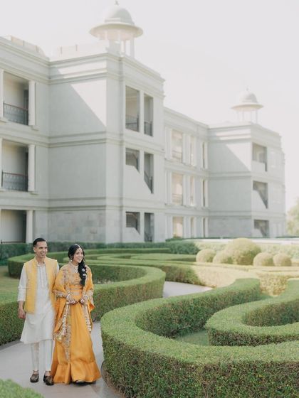 Mehul and Divya walking through the manicured gardens of their Udaipur venue. This shot captures a relaxed and happy moment during their Haldi celebrations.