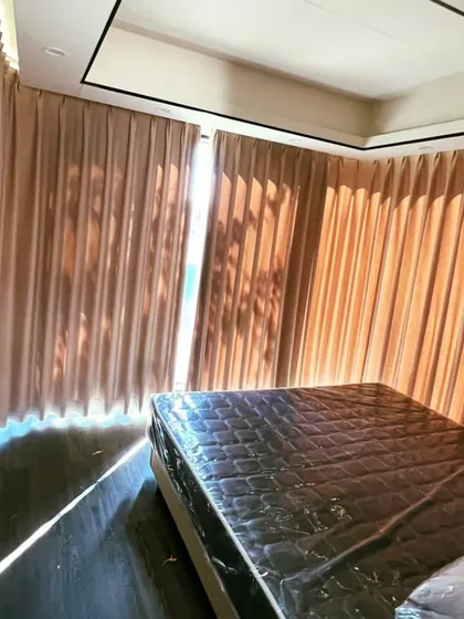 The bedroom in the Space Capsule E8, shown here with protective wrapping still on the mattress. The room is surrounded by large windows and elegant curtains for privacy.