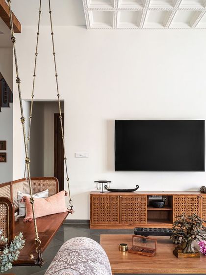 The living room is a perfect blend of comfort and tradition, featuring a classic wooden swing and a media cabinet with intricate jaali work.