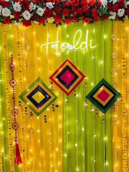 A bright and modern Haldi backdrop with a neon sign. The lime green and yellow drapes are decorated with marigold garlands and colorful geometric hangings for a fun, contemporary look.