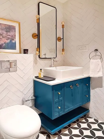 Even a small bathroom can have a big personality. For this master bath remodel, I used a striking combination of geometric floor tiles and herringbone wall tiles. The custom floating vanity in a bold teal, complete with an open shelf and mixed hardware, adds a pop of color and makes this compact space feel truly special.