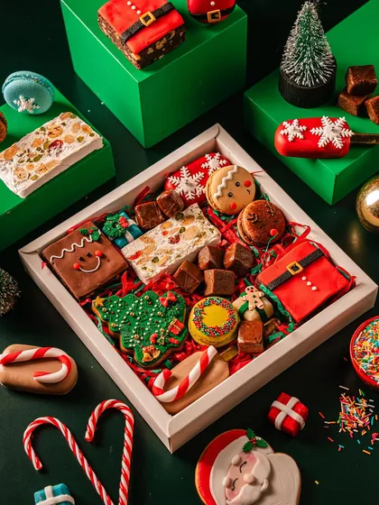 A festive treat box filled with a variety of Christmas goodies, including decorated cookies, macarons, cakesicles, and nougat. It's a perfect sampler of my holiday collection for a Secret Santa gift.