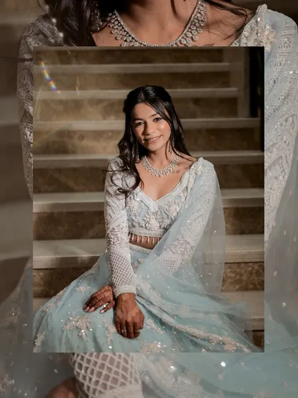 A creative, framed portrait of the bride seated on the stairs. The composition adds a modern touch to this elegant shot, focusing on her happy expression and detailed outfit.