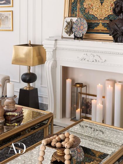 This detail shot highlights the mix of materials: the cool, reflective surface of the mirrored coffee table, the warm brass of the lamp, and the soft glow of the candles within the fireplace.