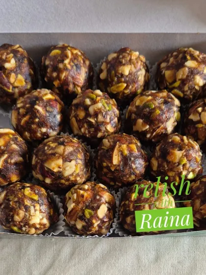 A detailed shot of the Dry Fruit Laddoos, showing the individual paper cups I use for neat packaging. The texture of the chopped nuts is clearly visible.