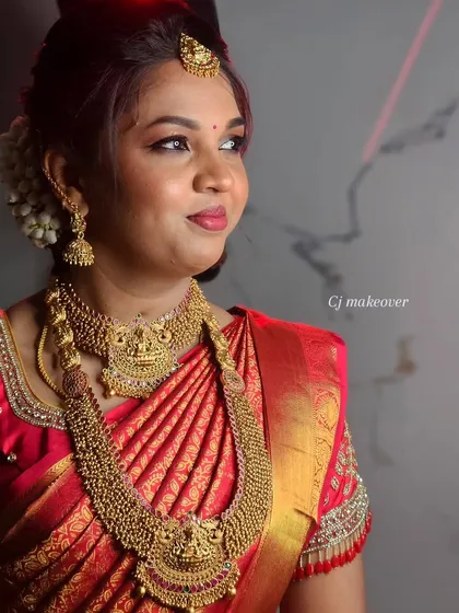 A side profile of this bride's muhurtham look, showing the flawless base and the beautiful detailing on her red saree and gold jewelry.