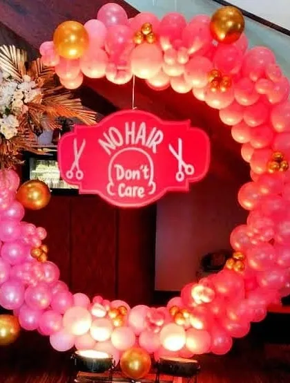 A slightly different angle of the pink and gold 'No Hair Don't Care' mundan party setup. The lighting from below makes the pink balloons glow, creating a warm and festive look.