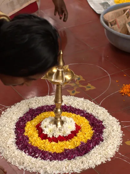 A staff member carefully creates a 'Pookalam', a traditional floral carpet, for Onam. The intricate design and vibrant colors symbolize prosperity, harmony, and a warm welcome to all.