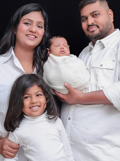 A beautiful portrait of a family of four, all dressed in white against a dark background. This creates a timeless and classic look.