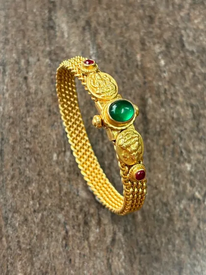What’s better than a silver product that looks exactly like gold? This is my 925 sterling silver kada with a thick gold plating, featuring temple coin motifs and a central green stone.