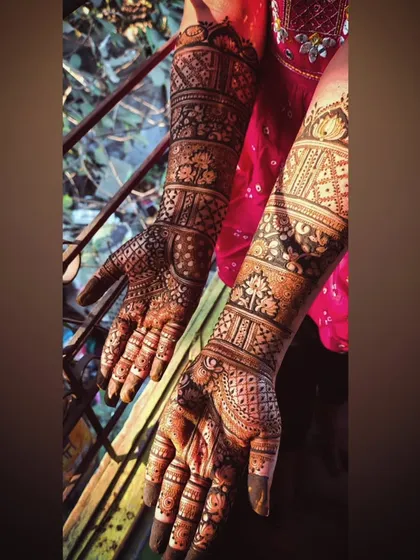 A stunning bridal design captured in natural light. The patterns extend from the palms to the elbows, featuring a mix of traditional Indian motifs and geometric grids.
