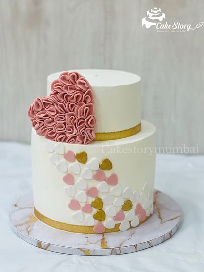 A simple yet elegant two-tier cake. The design features a cascade of pink and white hearts and is topped with a beautiful ruffled fondant heart.
