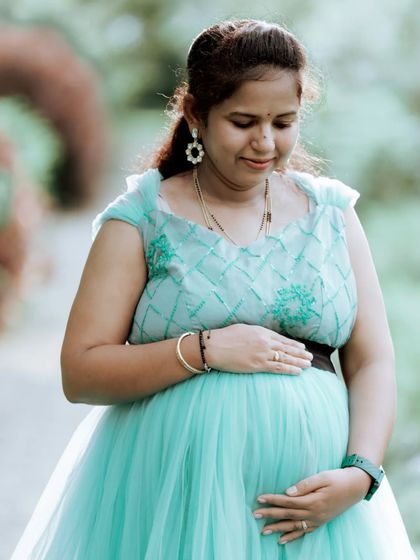 A close-up on the baby bump in this lovely sea-green maternity gown. The embroidered details on the bodice add a touch of delicate charm.