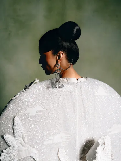 A close-up profile of a model wearing a Rahul Mishra creation. The focus is on the intricate sequin work, the unique earring, and the elegant line of the hair and neck.