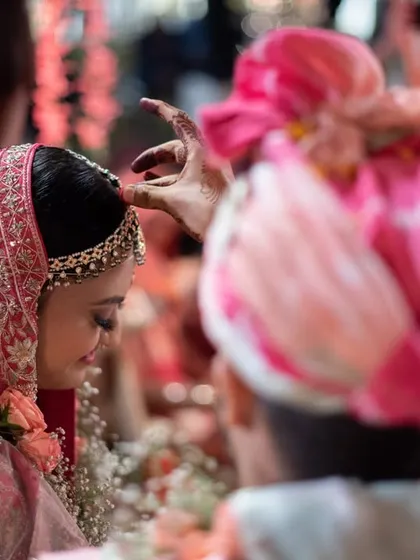 A close-up of the sindoor ceremony, shot from behind the groom to focus on the bride's serene expression.