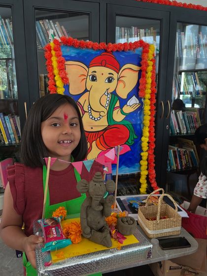 A smiling student with her completed Ganesha idol and decorated thali from our festive workshop.