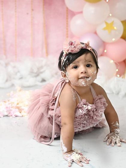 Crawling through the delicious mess. This action shot captures the fun and freedom of a cake smash session, with frosting on her hands, face, and knees.