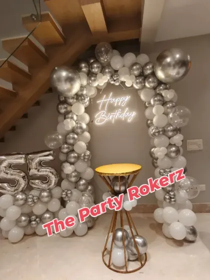 The 55th birthday home decor, complete with the balloon arch, neon sign, and a small table for the cake, creating a dedicated celebration corner.