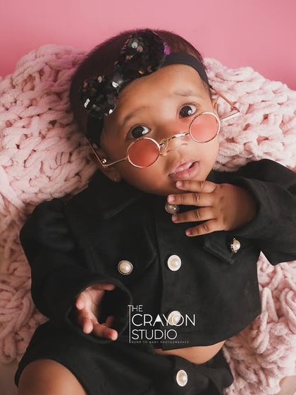 One of the twins looking cool and curious in her sunglasses during their stylish half-birthday shoot.