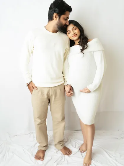 A tender moment between expecting parents, coordinated in soft white outfits. This minimalist setup keeps the focus purely on your emotion and connection.