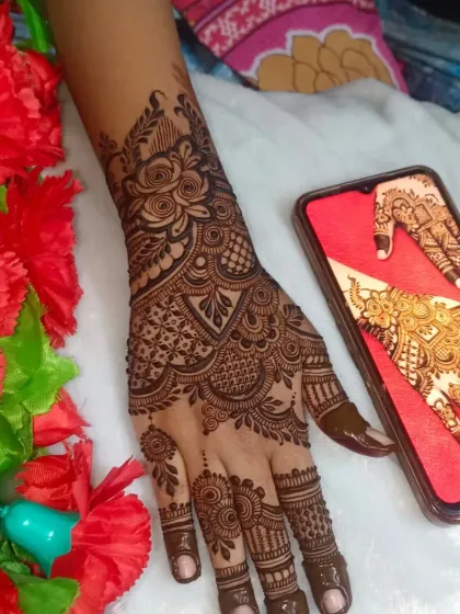 Another shot of this party henna, showing the design against a backdrop of red flowers.