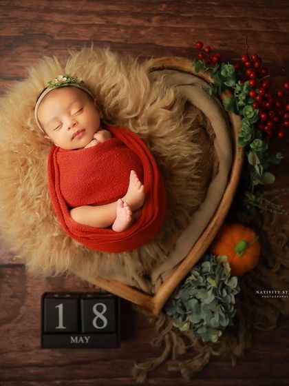 This baby is wrapped in a vibrant red swaddle and placed in our popular heart-shaped bowl. The surrounding props are kept minimal to let the baby be the star.
