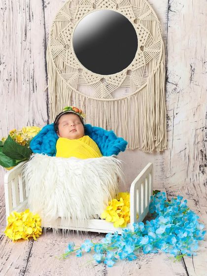 A pop of color makes this newborn portrait vibrant and cheerful. The combination of yellow, blue, and a boho-style mirror creates a unique and artistic look.