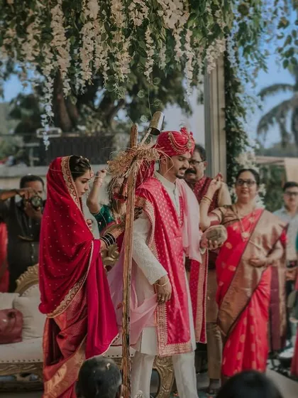 A candid shot from the pheras. The couple circles the sacred fire, their colorful traditional attire vibrant under the daytime sky, surrounded by their loved ones.