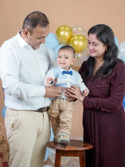 Helping their little one take his first "steps" during his birthday photoshoot. This is a beautiful way to document growth and the supportive hands of loving parents.