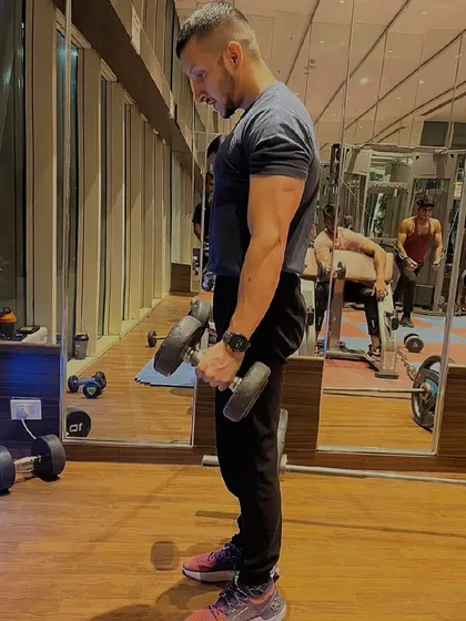 A side view of a dumbbell hammer curl. This variation helps target both the bicep and the brachialis muscle, leading to fuller-looking arms.