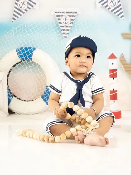 Holding onto his nautical rope, this baby boy looks like a seasoned captain in his sailor-themed photoshoot.