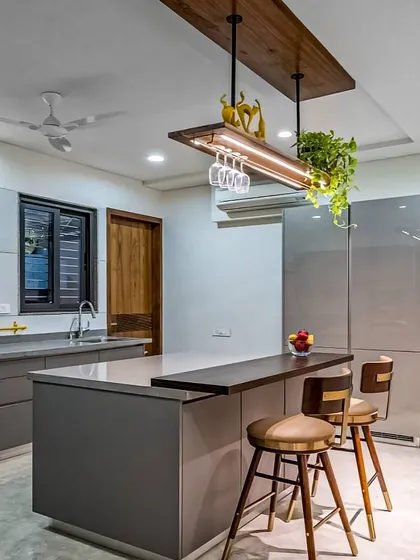 An island can transform a kitchen, and this design shows how. It features a sleek breakfast bar for casual meals, extra counter space for prep, and a custom overhead rack with integrated lighting and wine glass storage, blending style with practicality.