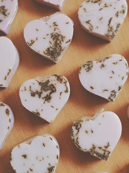Heart-shaped lavender milk soaps, some infused with real lavender buds for gentle exfoliation and a calming aroma.