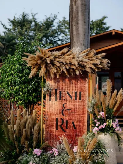 A personalized welcome sign with a rustic twist. The couple's names are set on a textured backdrop and surrounded by pampas grass, perfectly matching the boho-chic theme.