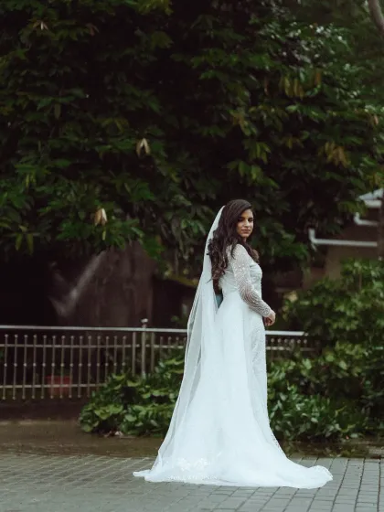 A full-length portrait of the bride, her long veil trailing behind her, creating a moment of timeless elegance.
