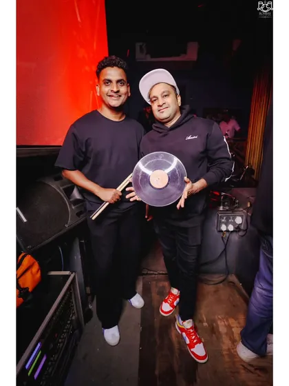 Holding up a clear vinyl record with my percussionist by my side. This represents our blend of classic DJ culture and live musical performance, a story told through beats and rhythms.