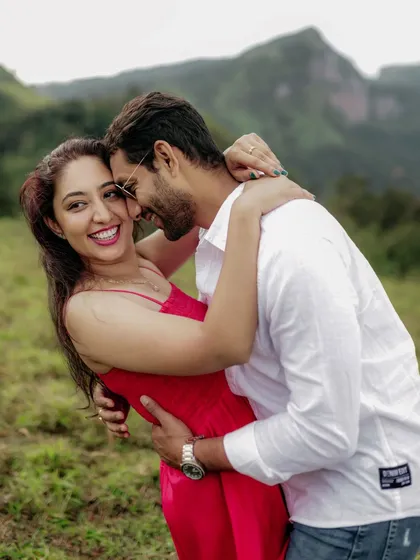 A happy, playful moment between a couple during their pre-wedding shoot in a beautiful green landscape, their laughter telling a story of love.