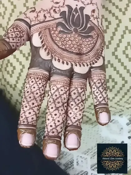 A close-up of a lotus-centric design on the palm. The fingers feature a delicate criss-cross pattern, which is a beautiful and popular filler element.