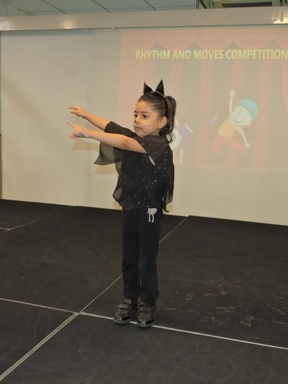 Dressed in a bat costume, a student gracefully performs her dance routine, expressing herself through the art of movement.
