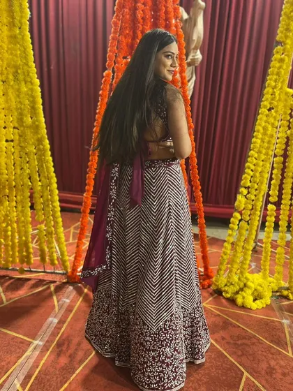 A back view of the client in the maroon chevron lehenga, highlighting the backless design of the blouse.