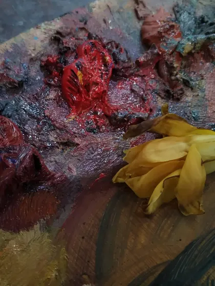 A close-up of my oil paint palette next to a flower. The thick, buttery texture of the paint is part of the impasto technique I love to use.